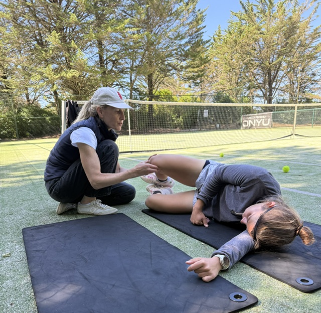 Naomi guiding an athlete beside a tennis court